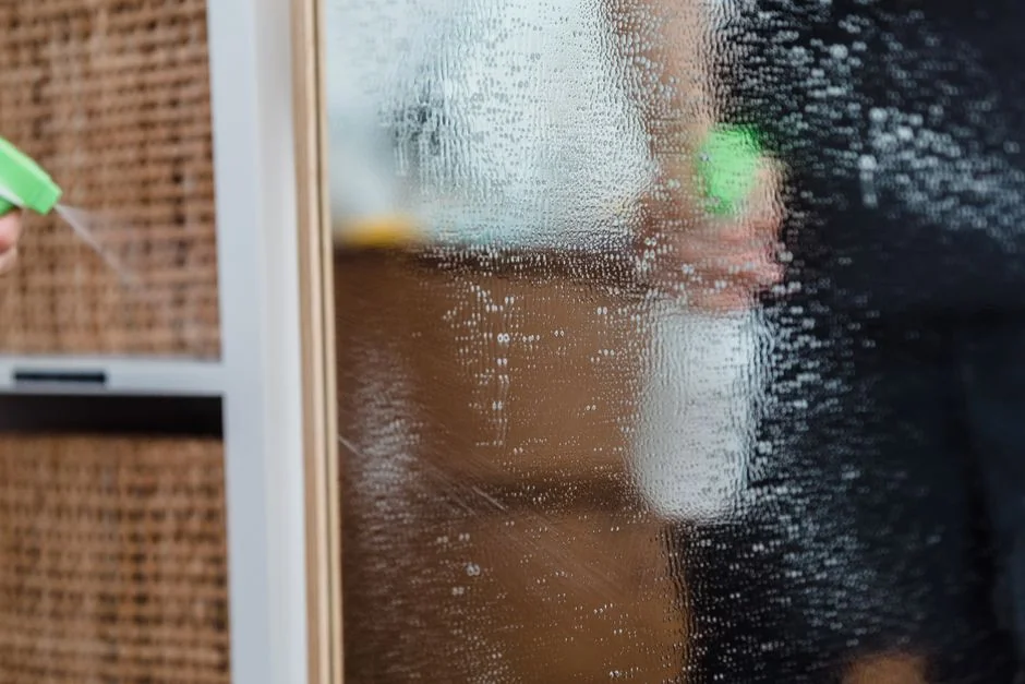 Minimalist room with a person cleaning a chair using a sponge and cleaning product.